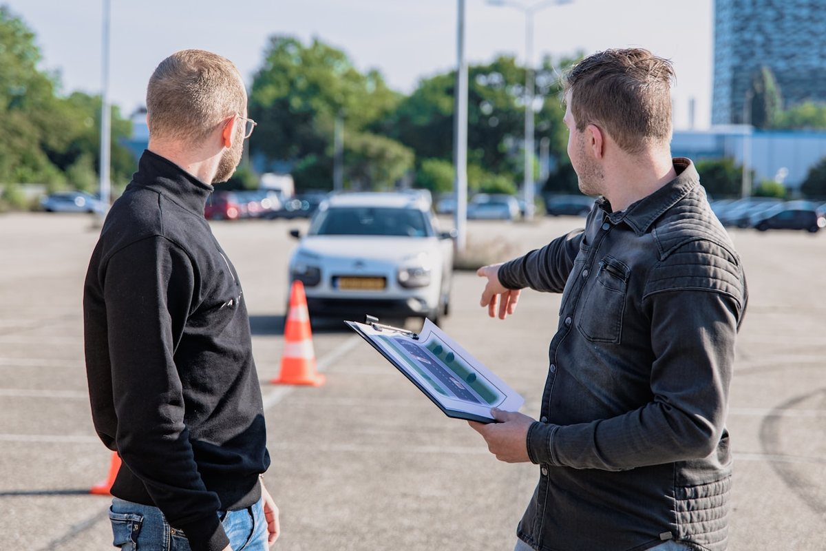 Zwei Personen begutachten ein Fahrzeug, einer hält ein Klemmbrett