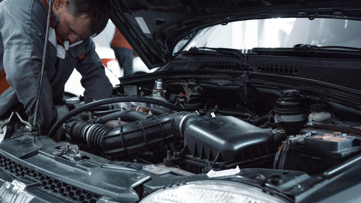 Mechaniker begutachtet den Motorraum eines Fahrzeugs in der Werkstatt