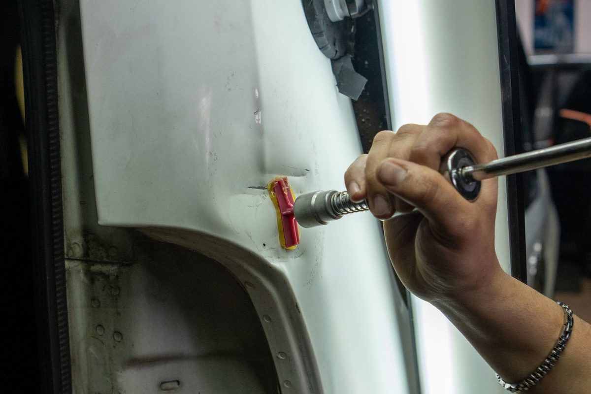 Ausbeularbeit an einer Fahrzeugt&uuml;r mit Zughaken in der Werkstatt